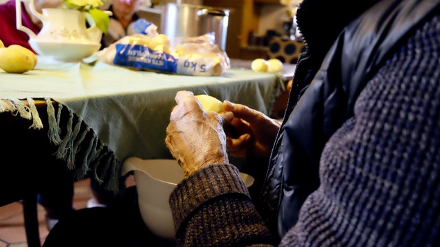 Anziano che sbuccia le patate.